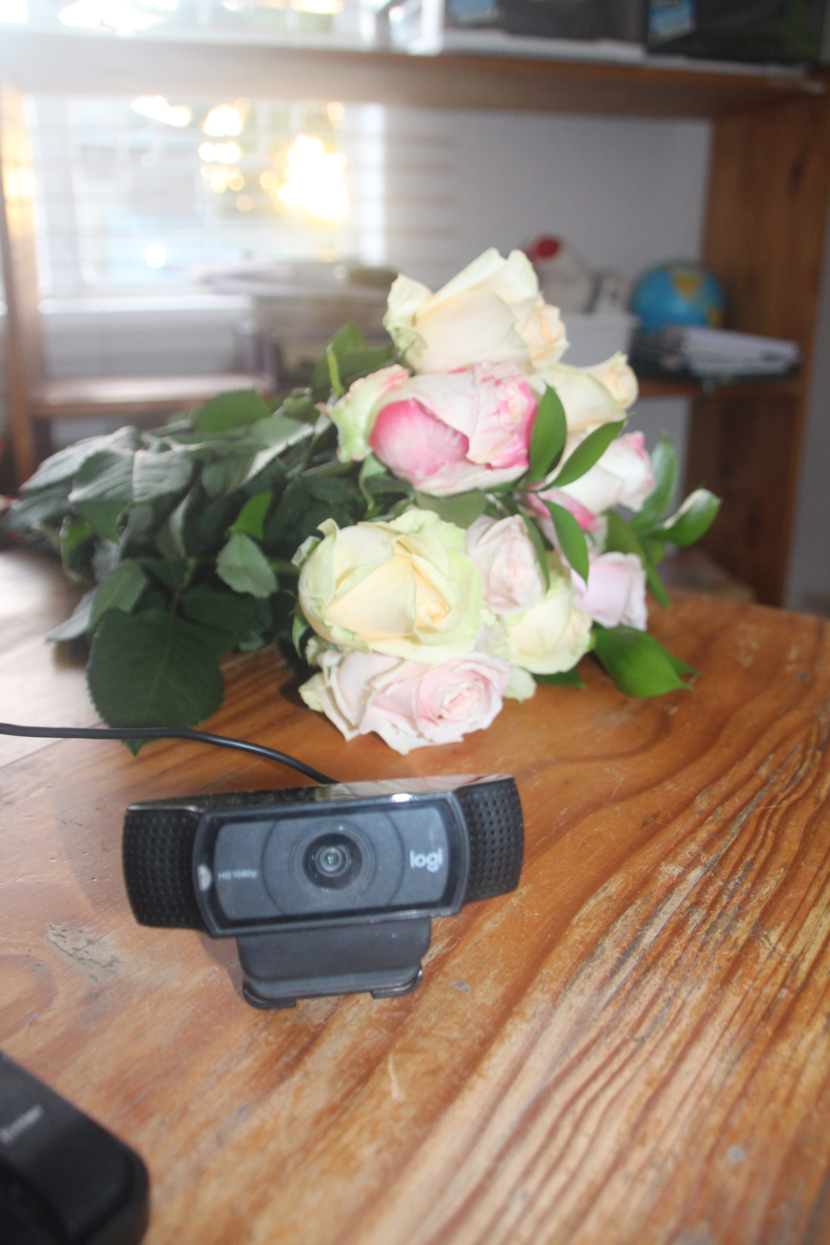 A webcam with some flowers on a desk